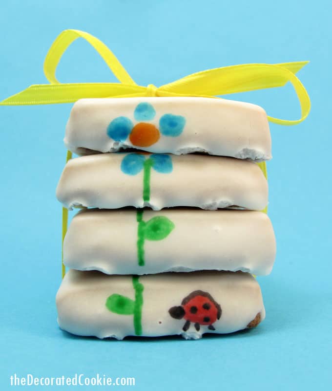 Stacked flower cookies for Spring with poured sugar icing and designs hand-drawn with food coloring pens.
