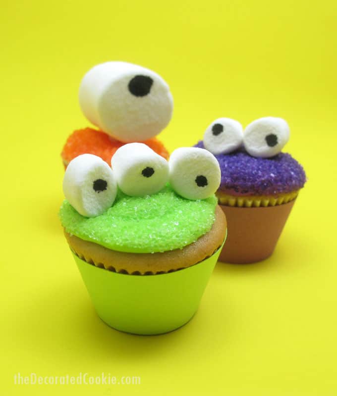 Mini monster cupcakes for a fun Halloween food idea -- marshmallow googly-eyes top sparkly cupcakes. Easy cupcake decorating.