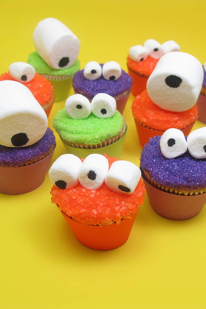Mini monster cupcakes for a fun Halloween food idea -- marshmallow googly-eyes top sparkly cupcakes. Easy cupcake decorating.