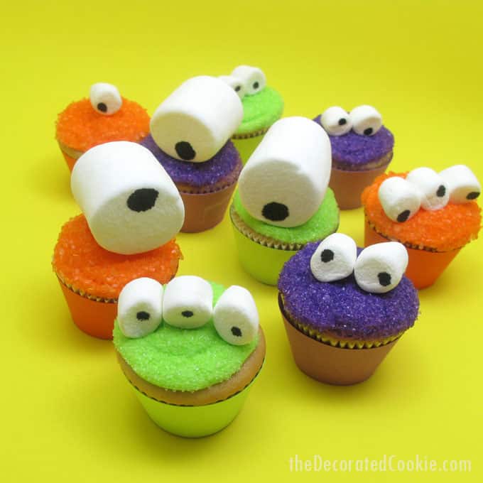 Mini monster cupcakes for a fun Halloween food idea -- marshmallow googly-eyes top sparkly cupcakes. Easy cupcake decorating.