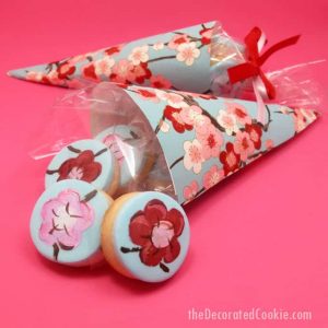 How to make painted cherry blossom decorated cookies in paper cones for beautiful spring party favors.  #papercones #weddingfavors #paintedcookies #cherryblossoms #flowers #partyfavors #fondant #spring