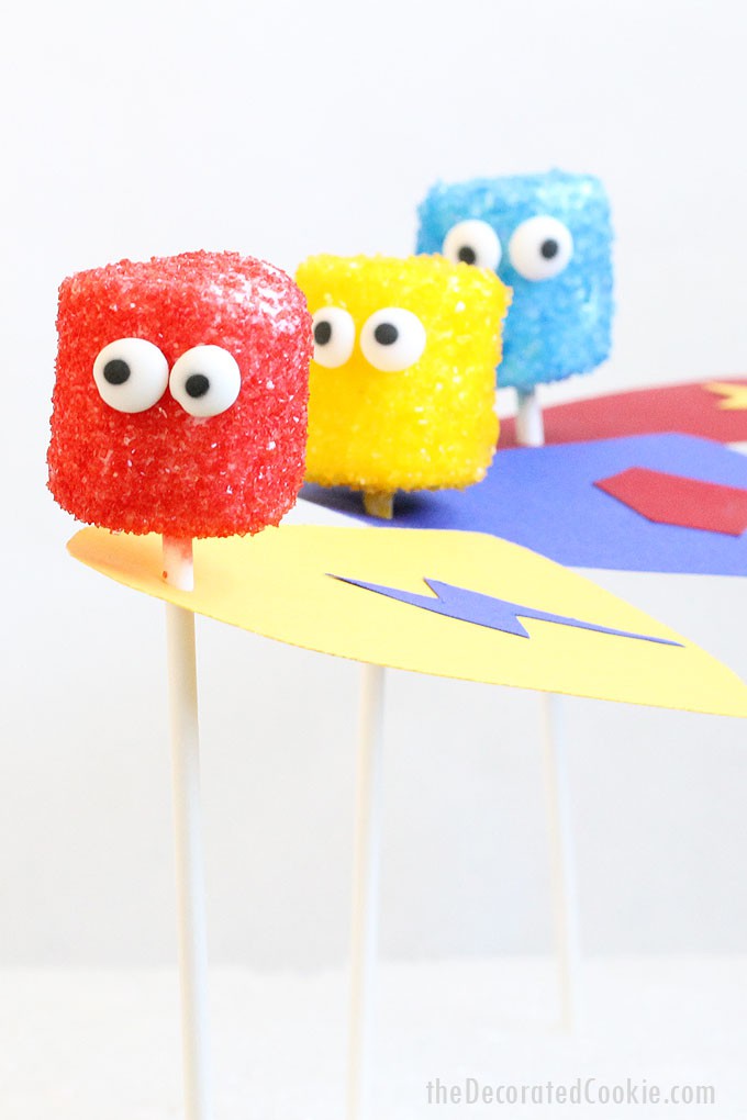 SUPERHERO MARSHMALLOW POPS -- Easy treat using sprinkles, candy eyes, and paper. Perfect food idea for superhero parties.