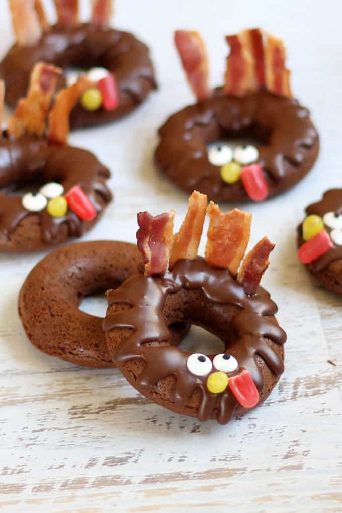 For the perfect Thanksgiving breakfast treat or fun food idea: BAKED CHOCOLATE DONUT TURKEYS. Bacon feathers, candy eyes. Video recipe. #thanksgiving #donuts #chocolatedonuts #bakeddonuts #turkey #funfood #thanksgivingfunfood