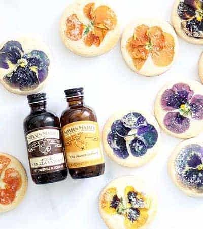 These gorgeous orange cookies with edible flowers are delicately flavored with orange extract and topped with a sprinkle of sugar. For afternoon tea, a lovely gift, or just to enjoy, these floral cookies are just right. These cookies use Nielsen-Massey's Pure Vanilla Extract and Pure Orange Extract. (Sponsored by Nielson-Massey) #NielsenMasseyPartner