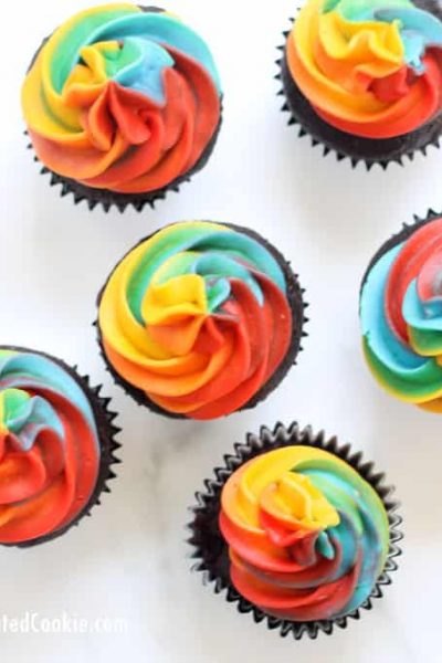 A step-by-step tutorial, with video, how to decorate rainbow swirl cupcakes with buttercream frosting. Easy, fun dessert for a rainbow or unicorn party. #rainbowfood #unicornfood #RainbowParty #cupcakes #buttercreamfrosting #RainbowSwirl