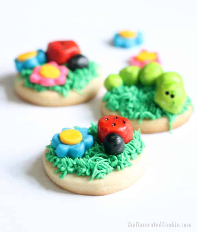 FROSTING CLAY: How to turn buttercream frosting into a delicious alternative to fondant. Sculptable frosting is perfect for cake and cookie decorating. Here, I made grass-topped decorated cookies with buttercream frosting clay BUGS and FLOWERS. #cookiedecorating #buttercreamfrosting #candyclay #fondant #cookies #bugs 