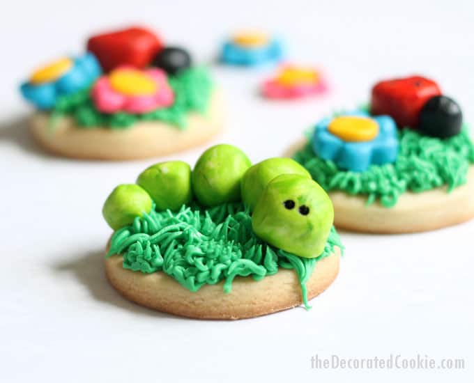 FROSTING CLAY: How to turn buttercream frosting into a delicious alternative to fondant. Sculptable frosting is perfect for cake and cookie decorating. Here, I made grass-topped decorated cookies with buttercream frosting clay BUGS and FLOWERS. #cookiedecorating #buttercreamfrosting #candyclay #fondant #cookies #bugs