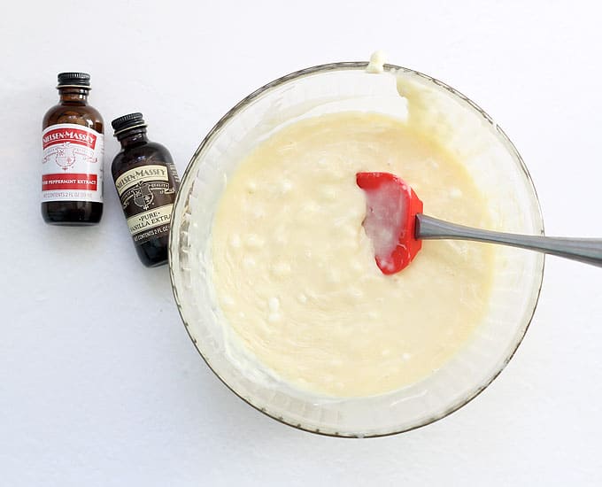 melted white chocolate in bowl with bottles of extracts
