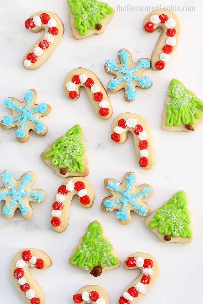 These sparkly MINI CHRISTMAS COOKIES are topped with sprinkles and easy to decorate. Package in tins for a holiday gift idea. #christmascookies #cookiedecorating #minichristmascookies #christmastree #snowflakecookies #candycanecookies