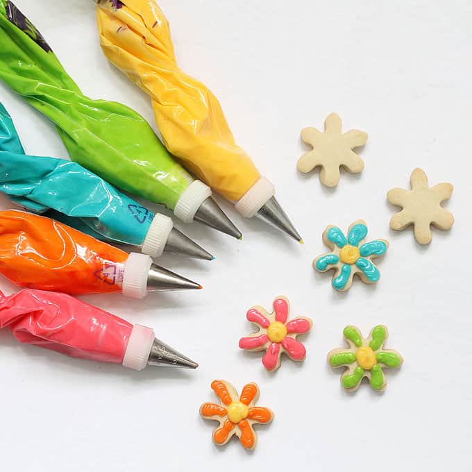 How to decorate MINI DAISY COOKIES with royal icing on cut-out sugar cookies. Colorful flower cookies for Spring or Mother's Day. Package in mason jars for a homemade gift idea. 