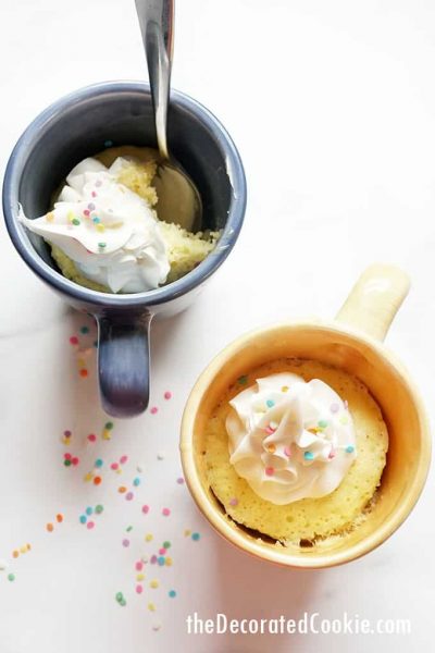 vanilla microwave mug cakes with frosting and spoon